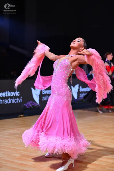 Dancesport competitor: Female dancer in foreground: pink ballroom gown with a sequined bodice, long flo