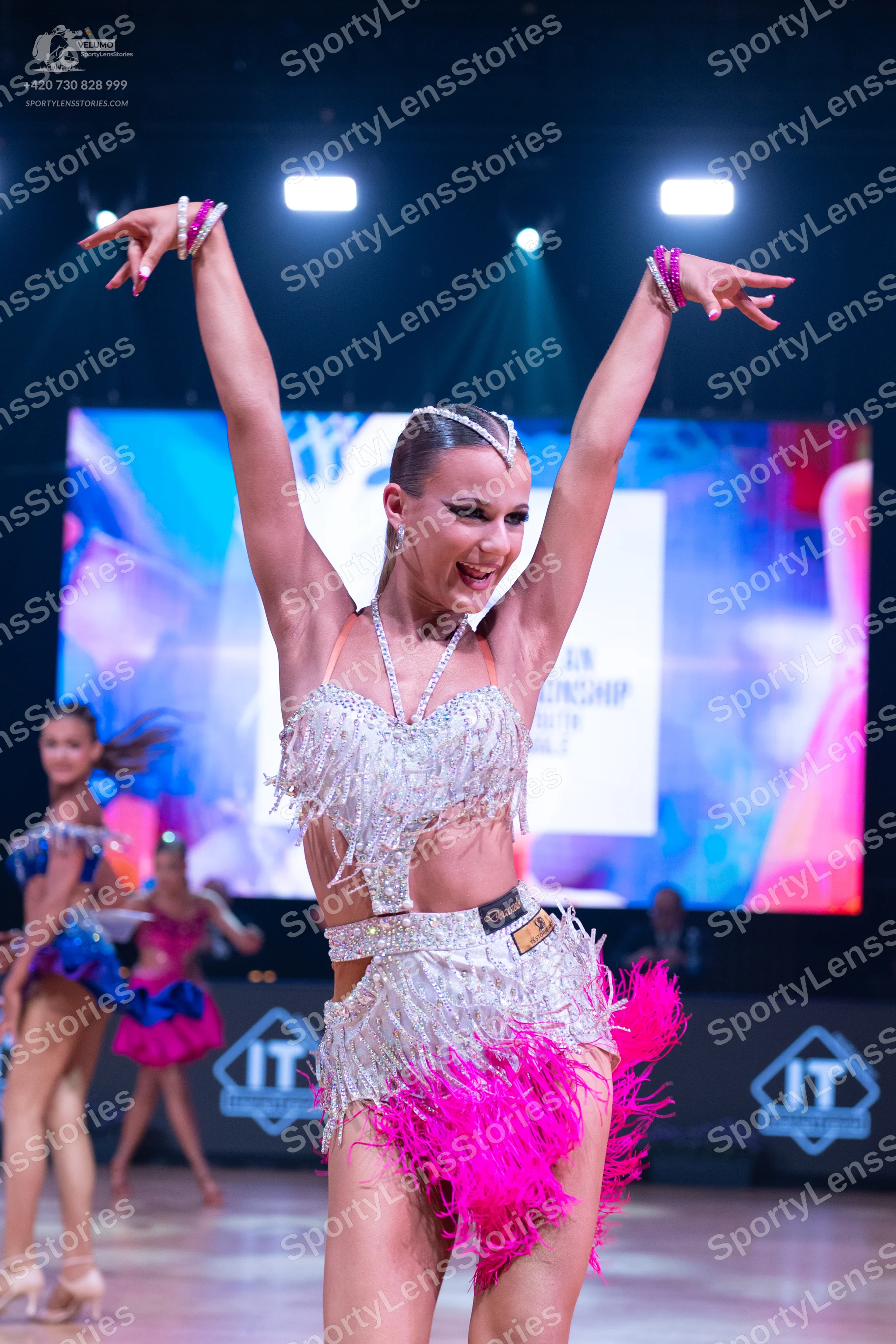 Dancesport competitor: Main dancer: silver sequin latin costume with white fringe and a large, bright p