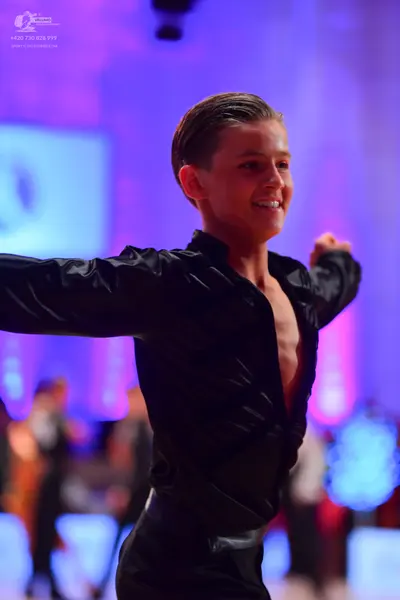 Dancesport competitor: Male dancer: black shiny long-sleeved top with an open chest and matching black 