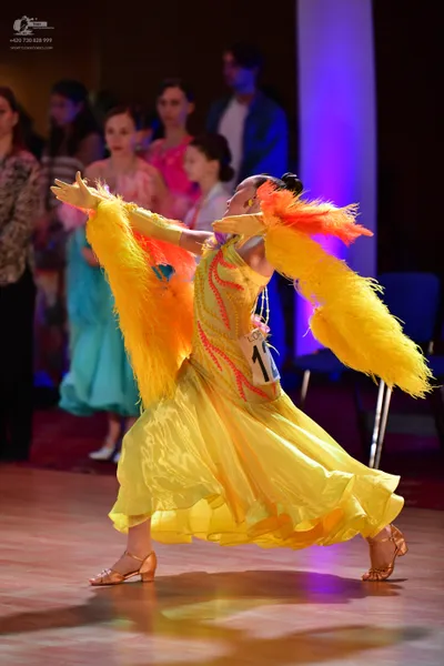 Dancesport competitor: Main female dancer: bright yellow ballroom dress with large yellow feather-like 