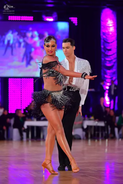 Dancesport competitor: Female dancer: black latin dress with silver fringe and a large cuff bracelet