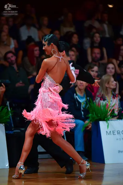 Dancesport competitor: Female dancer: pink latin dress with extensive fringe and a backless design, acc