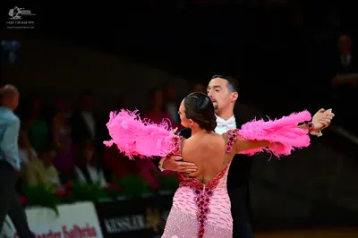 Dancesport competitor: Female dancer: pink Latin dress with pink feather sleeves and heavy sequin and b