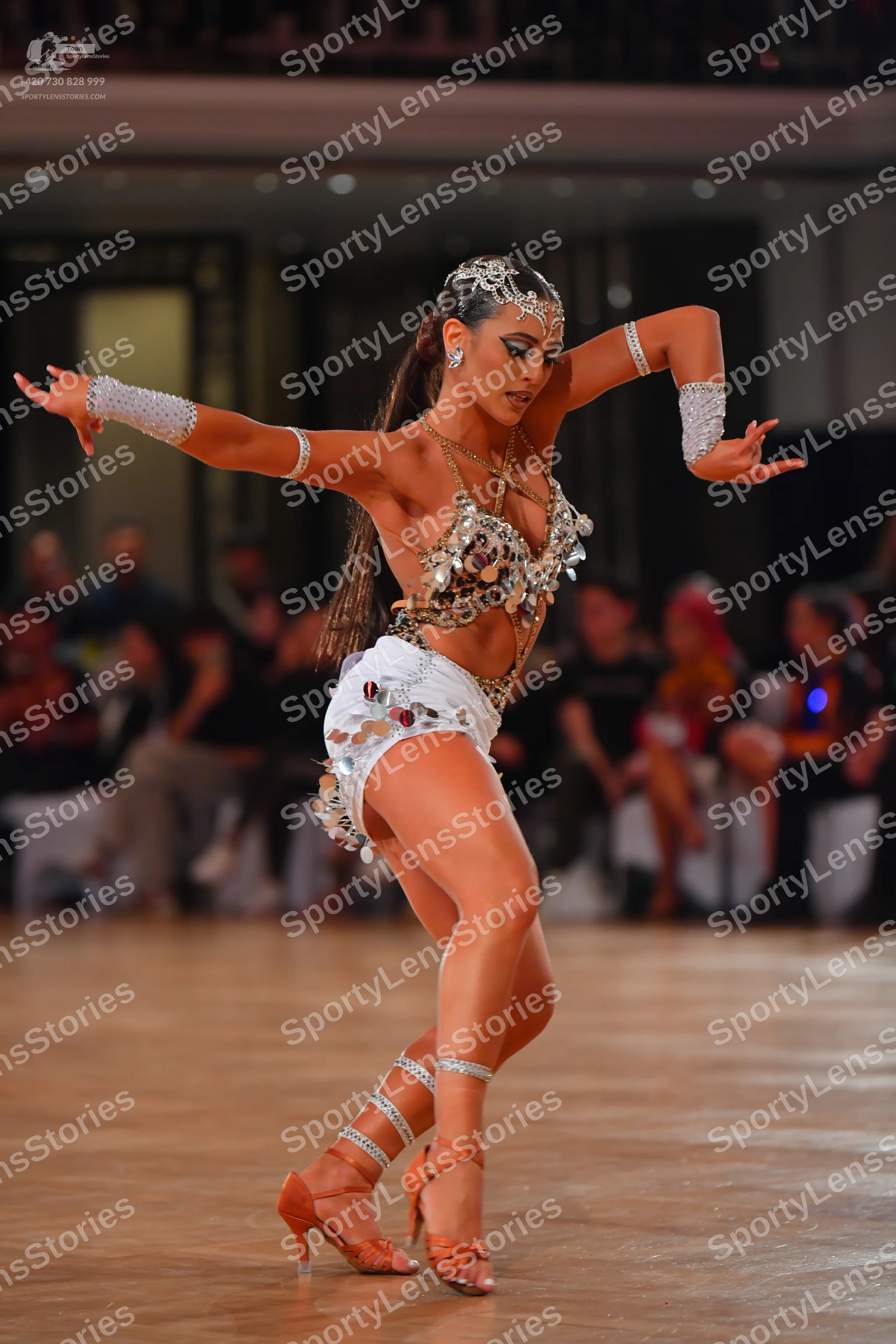 Dancesport competitor: Female dancer: white latin dance costume heavily embellished with large silver s