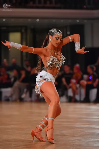 Dancesport competitor: Female dancer: white latin dance costume heavily embellished with large silver s