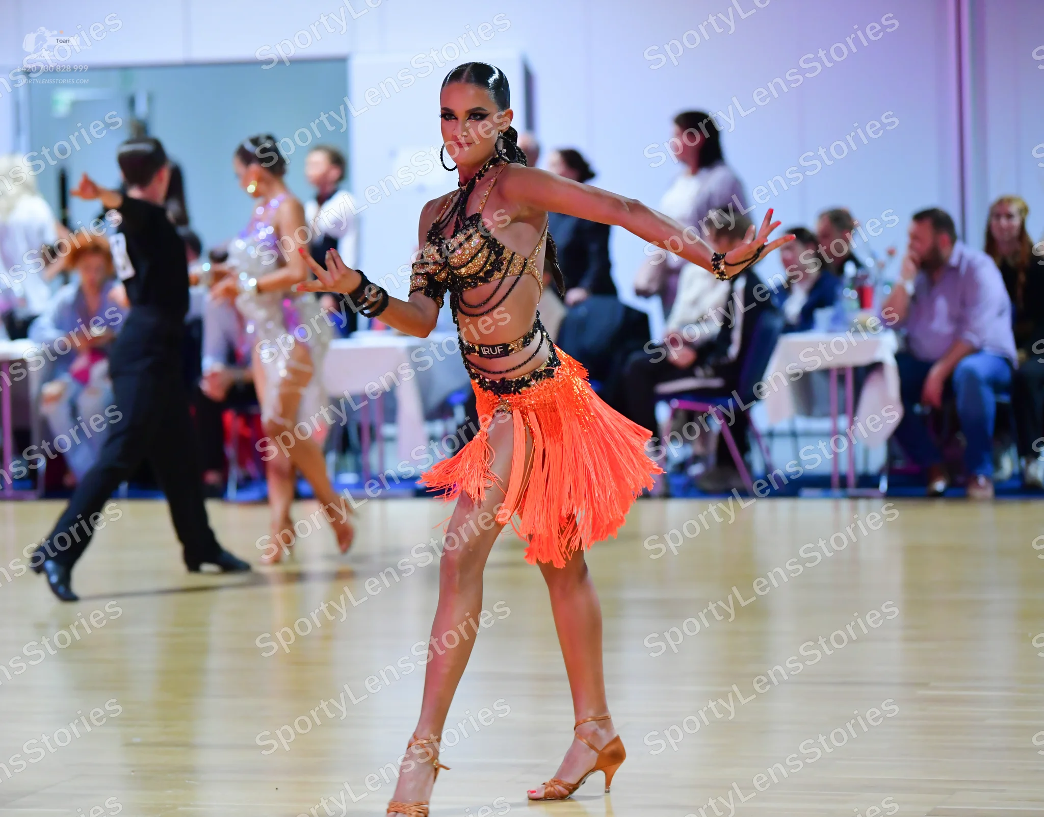 Dancesport competitor #145: Foreground dancer: orange Latin dress with a black sequined halter top and a lay
