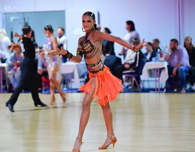 Dancesport competitor #145: Foreground dancer: orange Latin dress with a black sequined halter top and a lay