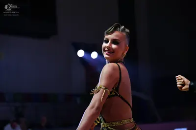 Dancesport competitor: Female dancer: black Latin dance costume with gold sequin/glittery patterns on t