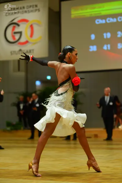 Dancesport competitor: Female dancer: white Latin dance dress with a ruffled skirt and sparkling embell