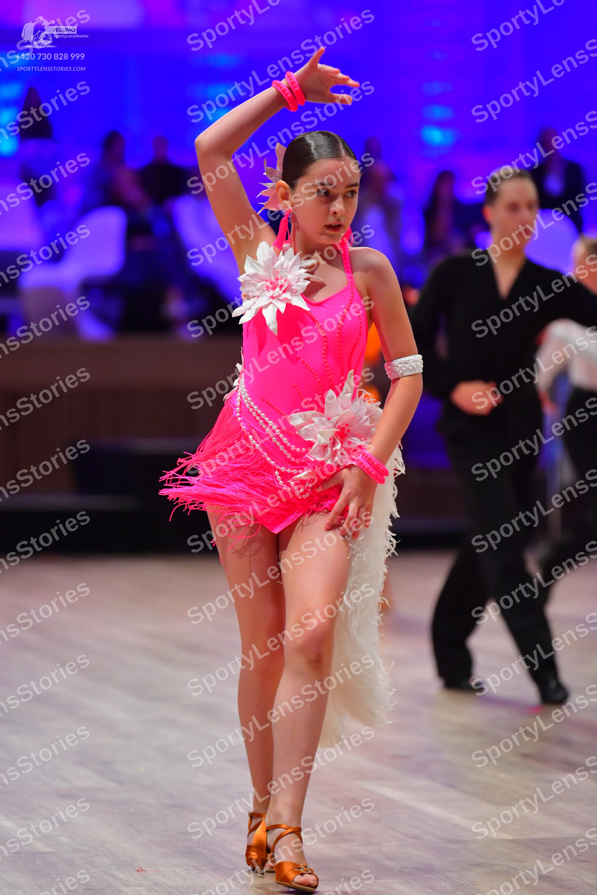 Dancesport competitor: Female dancer: bright pink latin dress with fringe, featuring large white floral
