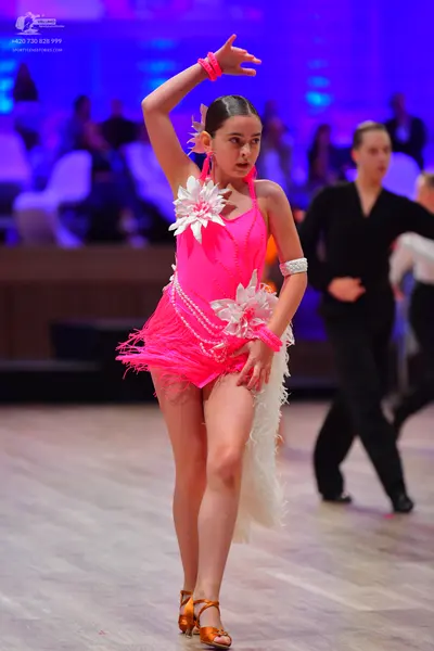 Dancesport competitor: Female dancer: bright pink latin dress with fringe, featuring large white floral