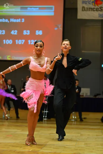 Dancesport competitor: Female dancer: pink two-piece latin costume with fringe-like layers, large hoop 