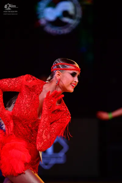 Dancesport competitor: Female dancer: red latin dress with sequins and fringe, red headband and red ear