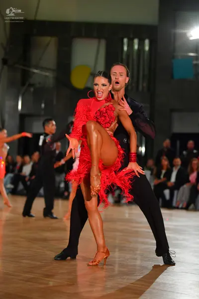 Dancesport competitor: Female dancer: red latin dress with fringe and feathers, large red hoop earrings