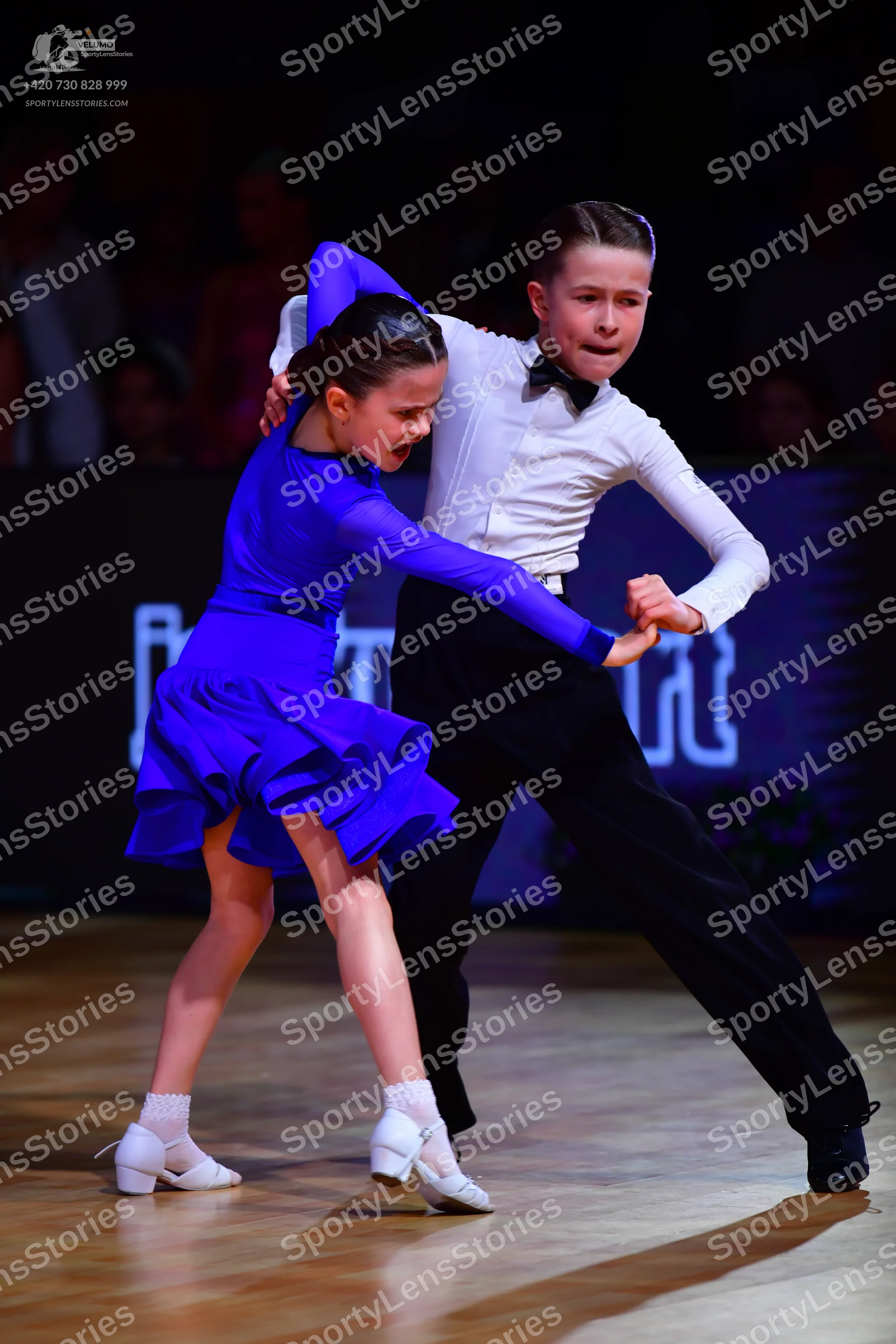 Dancesport competitor: Female dancer: royal blue long-sleeved latin dress with a flared skirt, white so