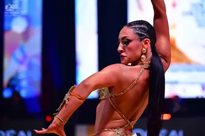 Dancesport competitor: Female dancer: nude-colored Latin dance costume with heavy gold sequin or crysta
