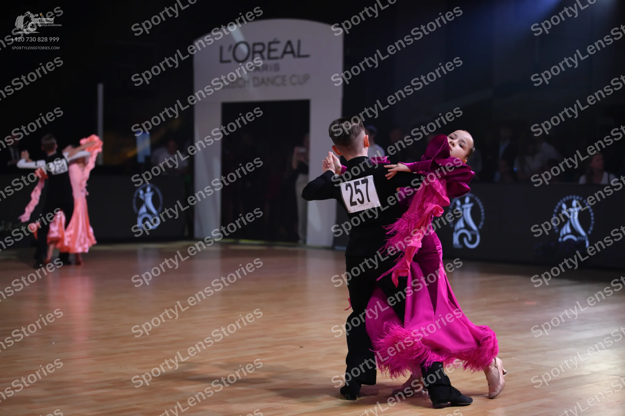 Dancesport competitor: Male dancer in foreground: black ballroom attire consisting of a black waistcoat