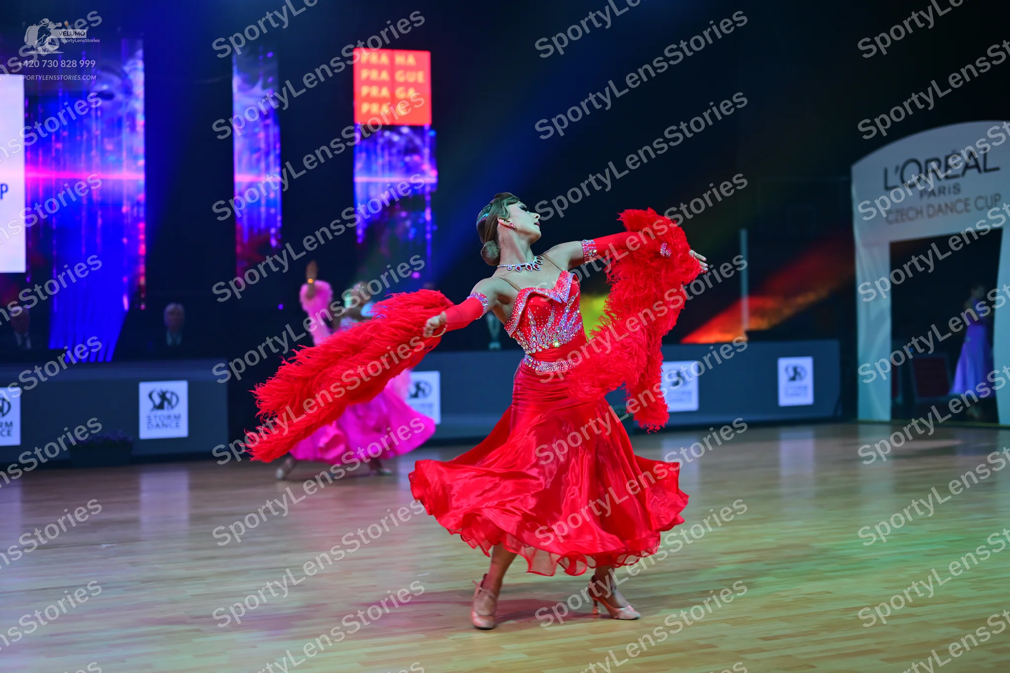 Dancesport competitor: Central female dancer: red latin dress with a voluminous ruffled skirt, matching