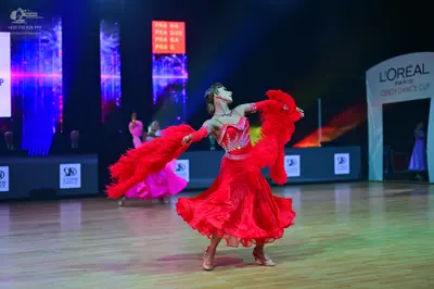 Dancesport competitor: Central female dancer: red latin dress with a voluminous ruffled skirt, matching
