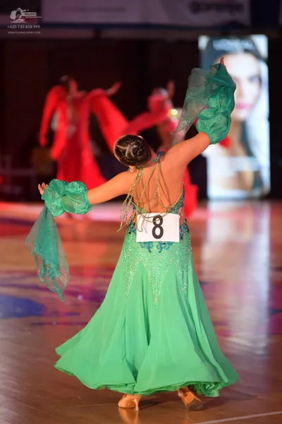 Dancesport competitor: Female dancer in foreground: bright green flowing dress with a sequined bodice a