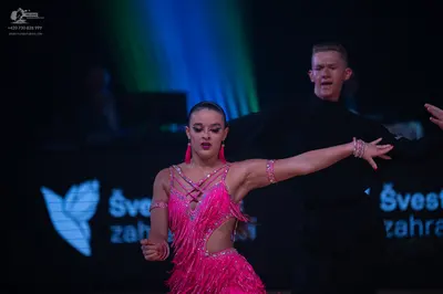 Dancesport competitor: Female dancer: pink latin dress with sequins and fringe, pink earrings, and brac