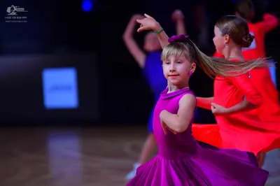 Dancesport competitor: Female dancer in foreground: magenta latin dress with smooth fabric and a matchi