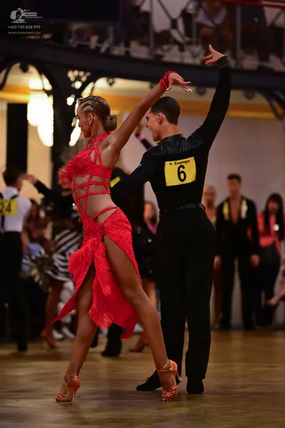 Dancesport competitor: Female dancer: red latin dress with lace, mesh, and cutouts