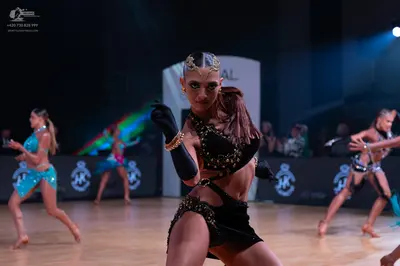 Dancesport competitor: Front dancer: black two-piece Latin costume with gold sequins, black opera-lengt