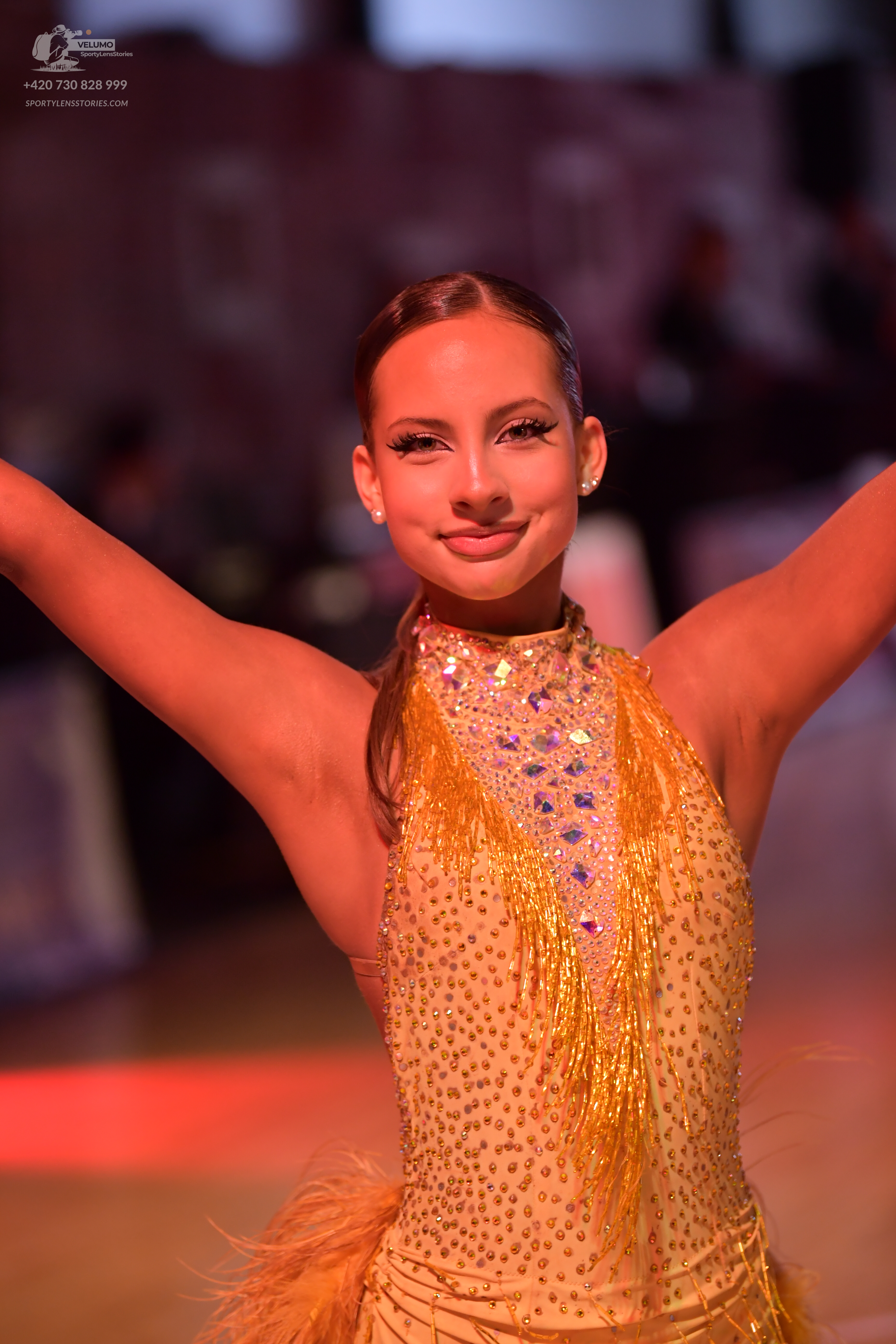 Dancesport competitor: Female dancer: gold Latin dance dress embellished with sequins and crystals, fea
