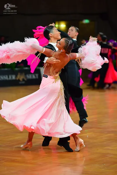 Dancesport competitor: Female dancer: light pink ballgown with gold sequin embellishments and large, fl