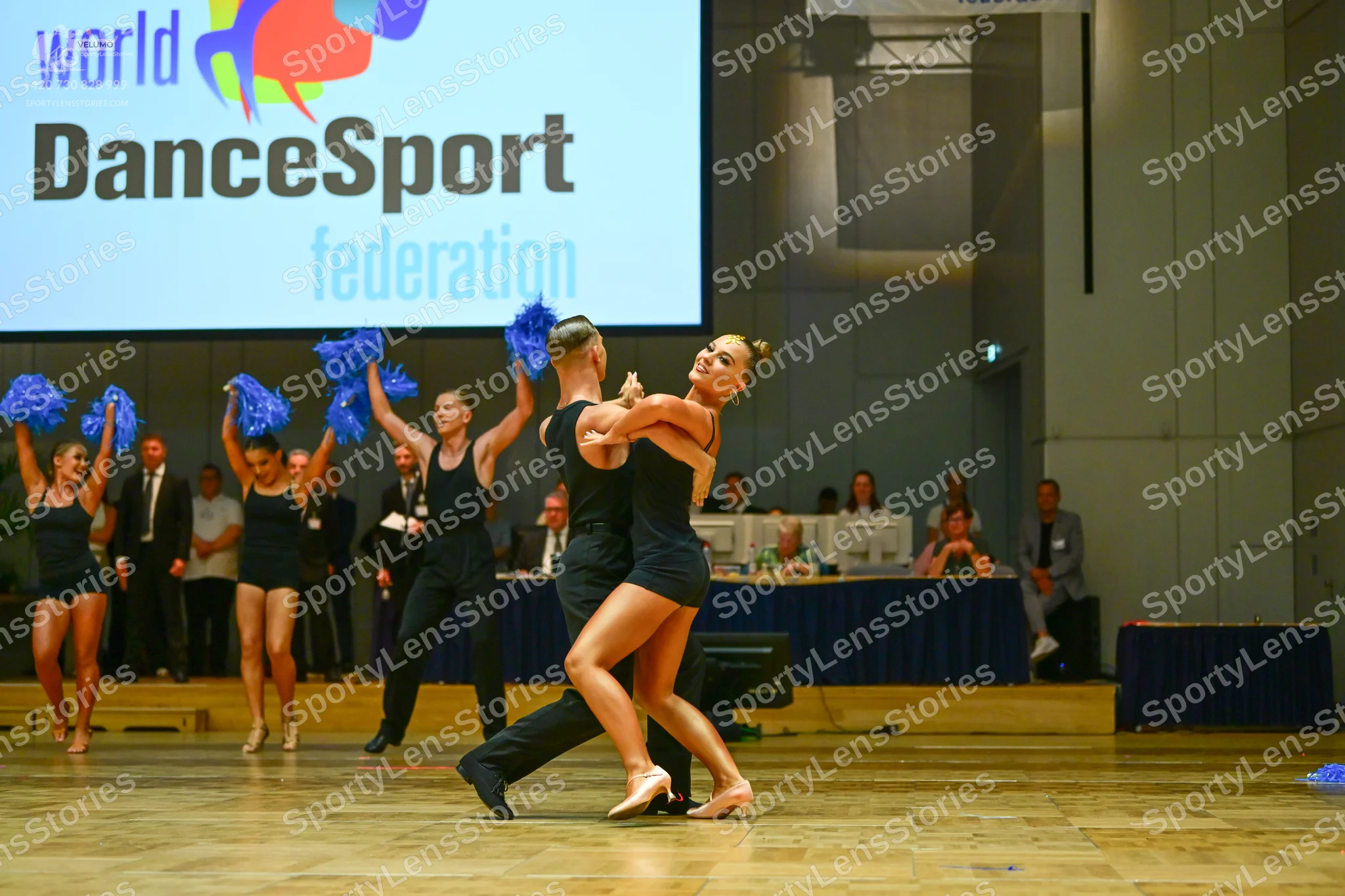Dancesport competitor: All dancers are wearing black dance costumes, including black sleeveless bodysui