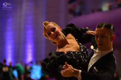 Dancesport competitor: Female dancer: black ballroom dress with voluminous sleeves and crystal embellis
