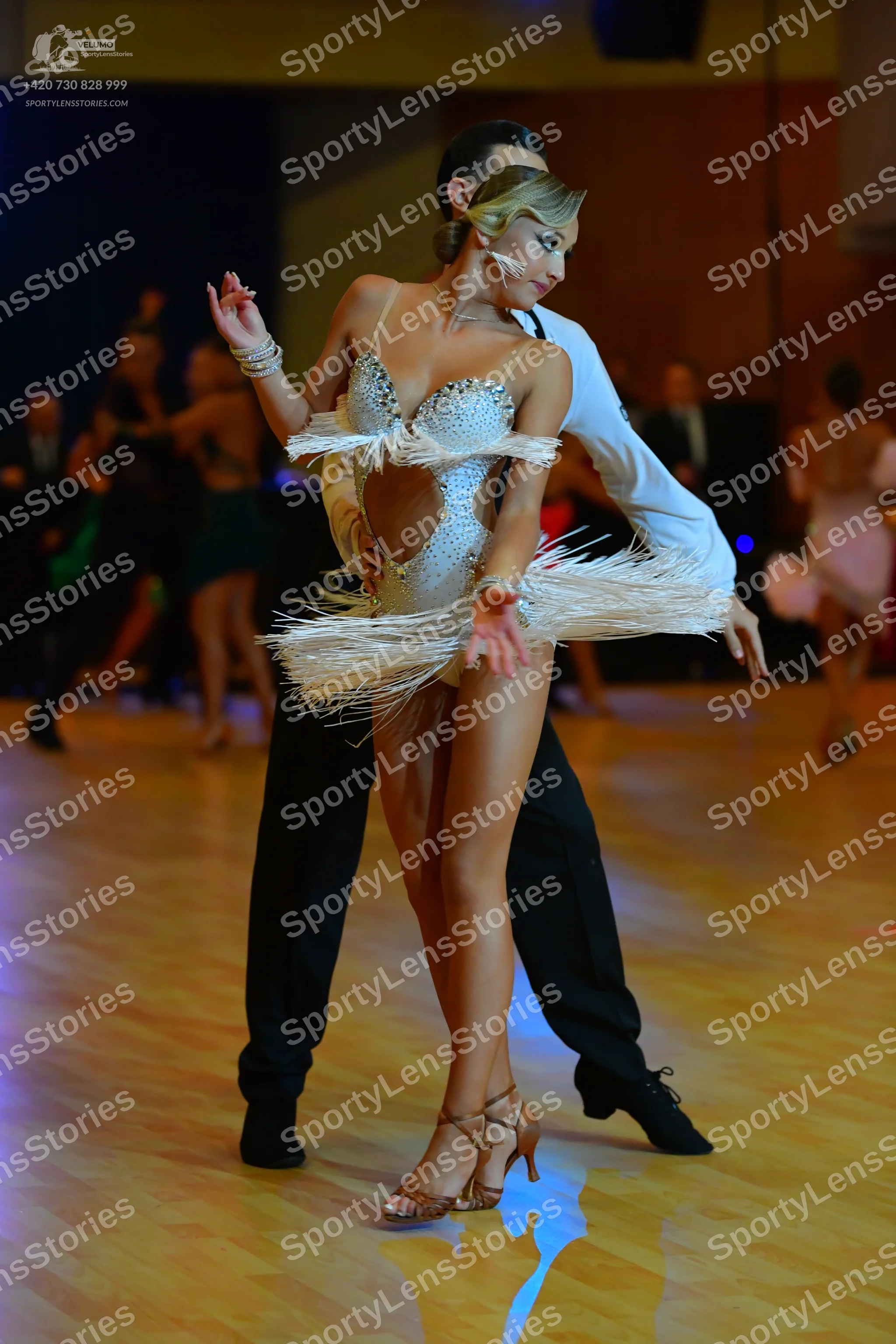 Dancesport competitor: Female dancer: light silver/white Latin dance leotard heavily embellished with s