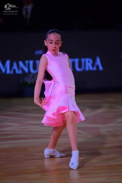 Dancesport competitor: Female dancer: bright pink sleeveless satin dress with a ruffled skirt