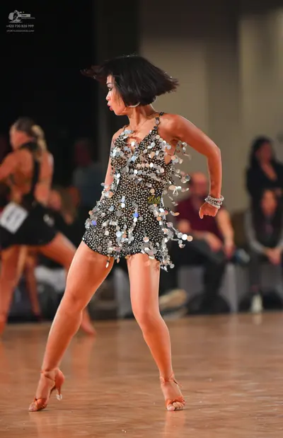 Dancesport competitor: Female dancer in foreground: black Latin dance dress heavily embellished with la