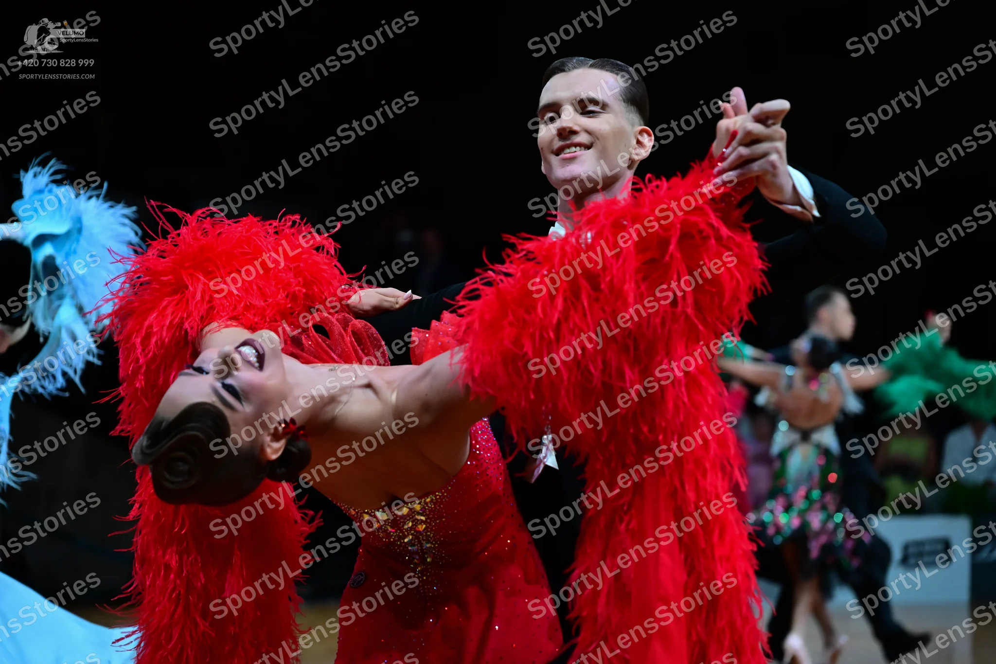Dancesport competitor: Main female dancer: red Latin dress with voluminous red feather fringes and sequ