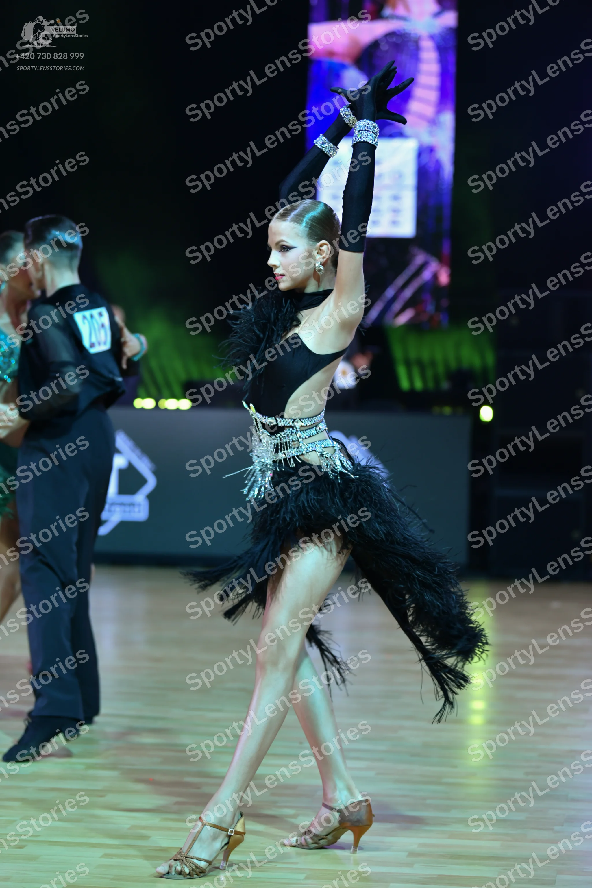 Dancesport competitor: Female dancer: black latin dance costume with long sleeves, a fringe skirt, and