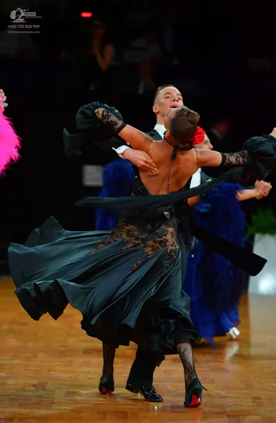 Dancesport competitor: Female dancer: black backless ballroom dress with a voluminous flowing skirt, bl