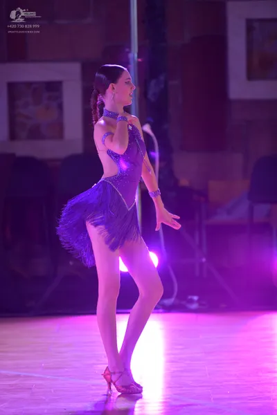 Dancesport competitor: Female dancer: purple Latin dress with sequins and fringe, and a matching wristb
