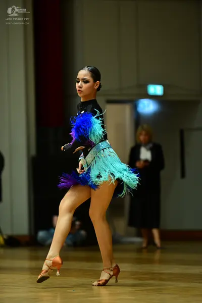 Dancesport competitor: Female dancer: black Latin dance dress featuring large, vibrant, multi-colored f