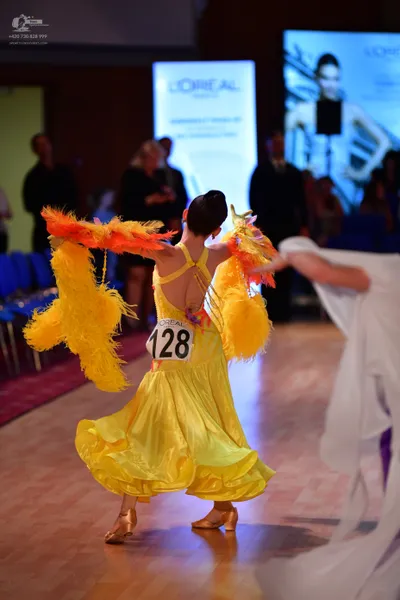 Dancesport competitor #128: Female dancer: yellow latin dress with large, voluminous yellow feather/fringe a