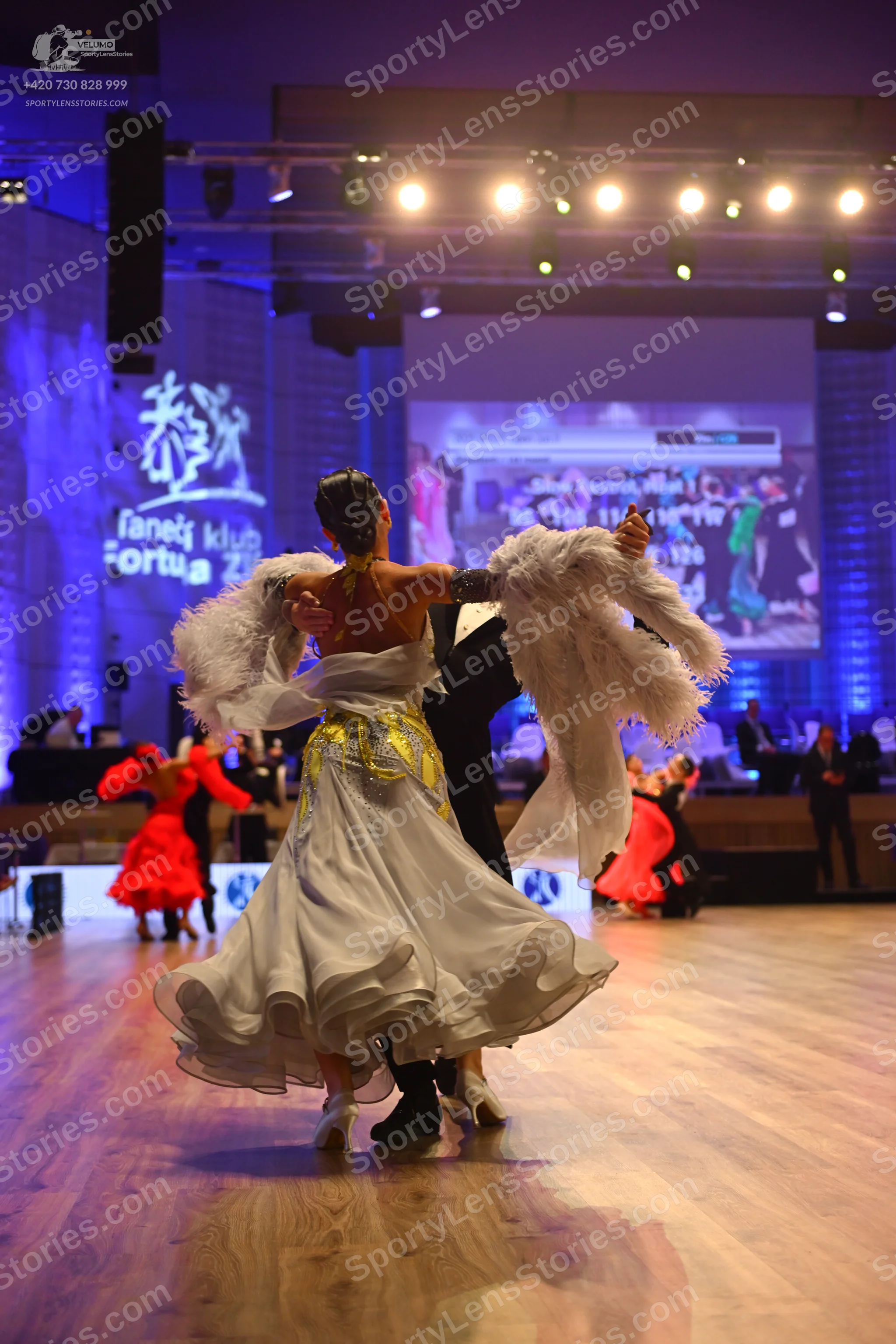Dancesport competitor: Female dancer: white ballgown with gold/yellow patterns on the bodice, a volumin