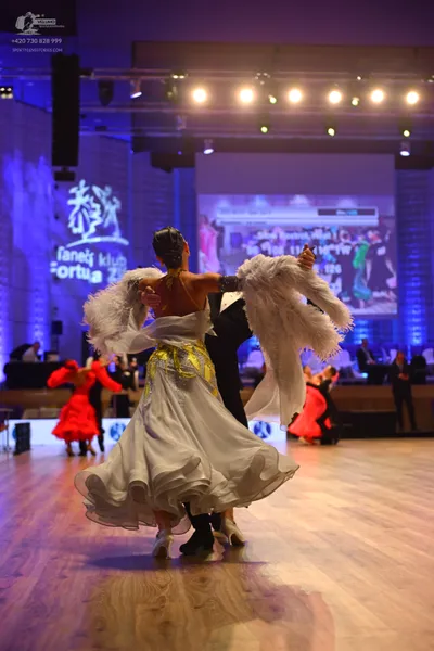 Dancesport competitor: Female dancer: white ballgown with gold/yellow patterns on the bodice, a volumin