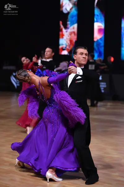 Dancesport competitor: Female dancer: purple ballgown with large purple feather trim on the shoulders a
