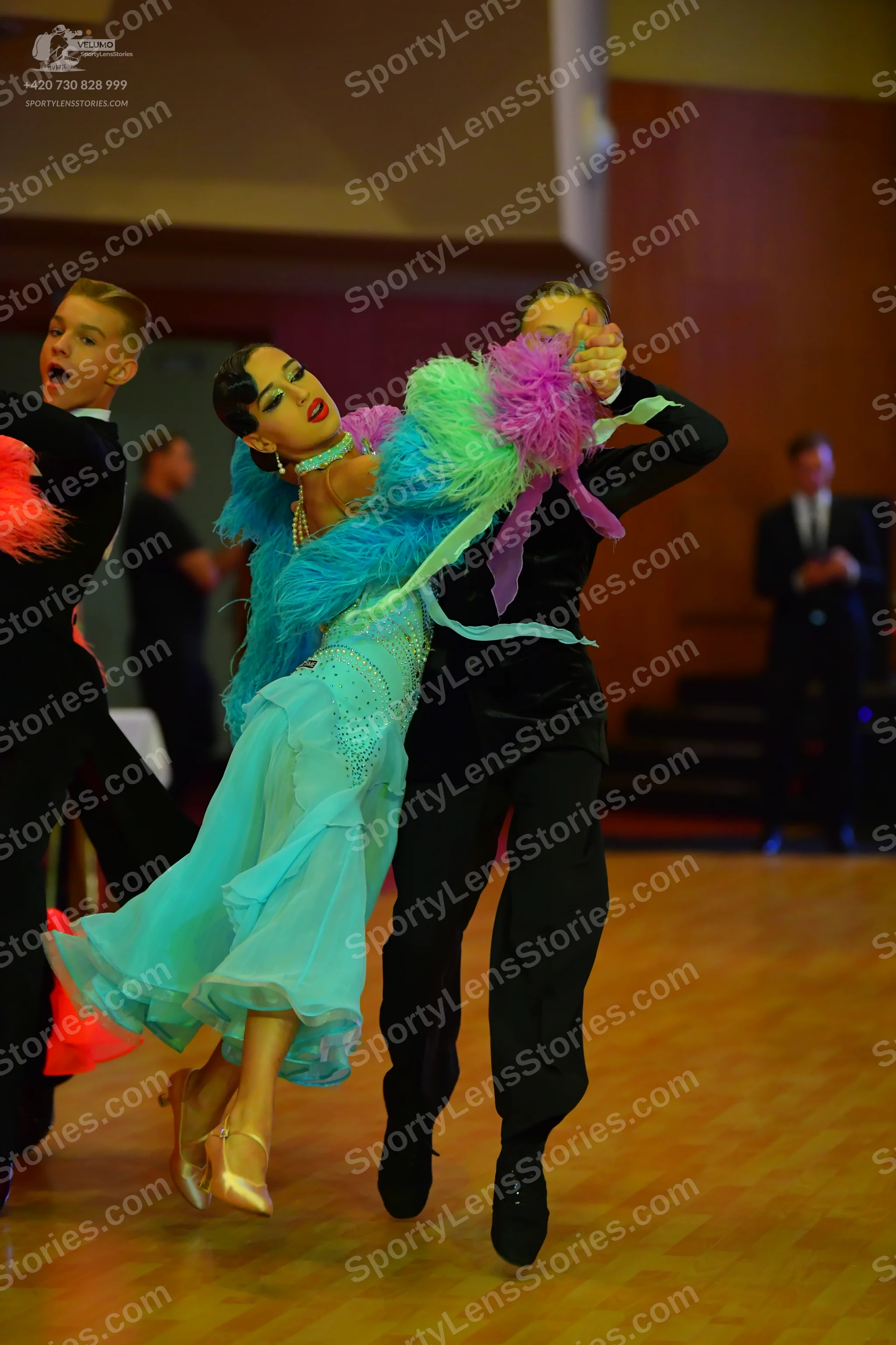 Dancesport competitor: Female dancer: aqua-colored Latin dress with colorful (blue, green, and purple)