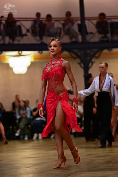 Dancesport competitor: Female dancer: red latin dress with cutouts and fringe, red earrings and red wri
