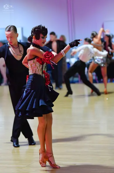 Dancesport competitor: Female dancer (foreground): black and red latin dance dress with a sequined bodi
