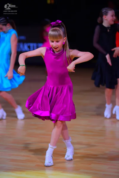 Dancesport competitor: Female dancer in foreground: magenta sleeveless dress with a high neckline and f