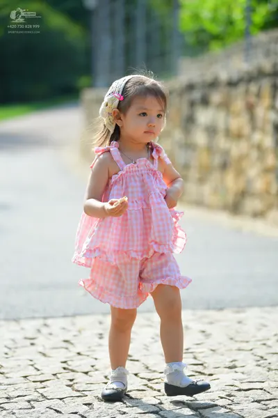 Dancesport competitor: Female dancer: pink and white gingham ruffled romper, white socks, and black Mar