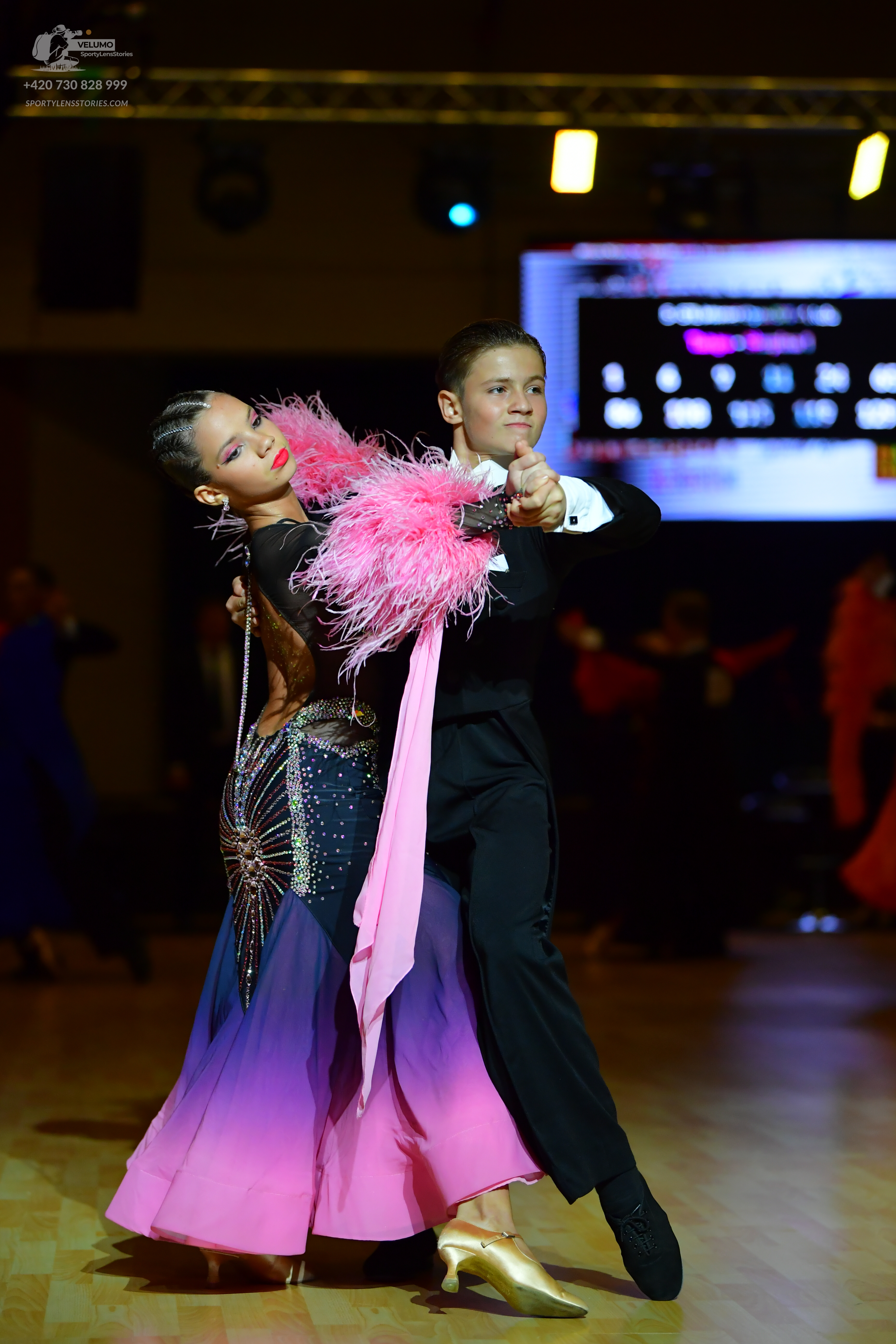 Dancesport competitor: Female dancer: dark ballroom gown with sequin embellishments, a pink, purple, an